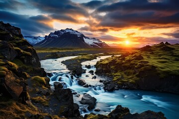 Obraz premium Breathtaking view of the sun setting behind a snow-capped mountain with a vibrant river in the foreground
