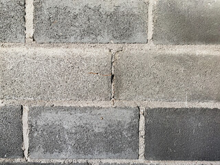 A white wall with a hole in it. The wall is cracked and has a rough texture