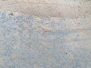 A white wall with a hole in it. The wall is cracked and has a rough texture