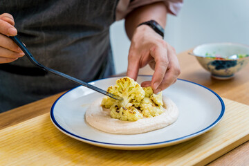 Chef at the kitchen preparing bean porridge with cauliflower and vegetables