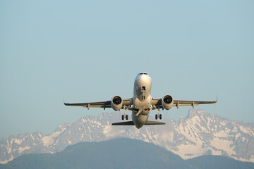 The plane takes off at an airport in the mountains. Airplane in the sky with mountains on the...