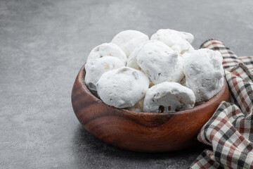 Traditional mini meringues with nuts in wooden bowl on gray background