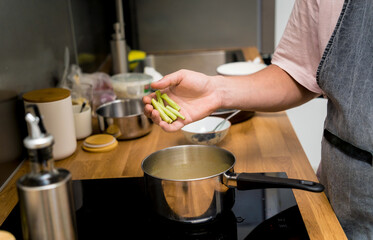 Chef at the kitchen preparing green curry with herbs and rice
