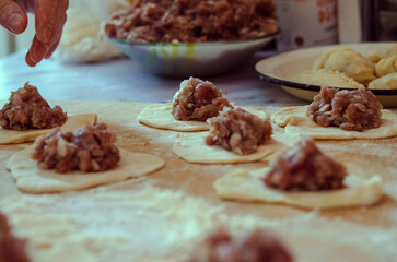 Chef's hands close-up making dumplings from dough. The process of preparing pelmeni with meat. Traditional Russian food