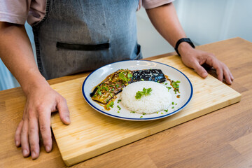 Chef at the kitchen preparing grilled eggplants with garlic