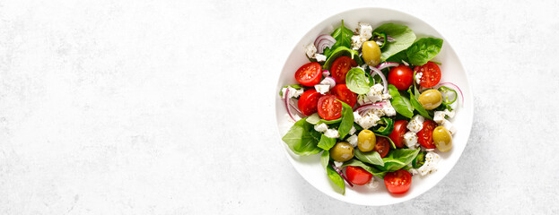 Fresh healthy vegetable Mediterranean salad of feta cheese, tomato, olives, green pepper and green basil leaves, banner,  top view