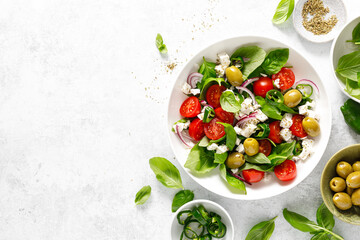 Fresh healthy vegetable Mediterranean salad of feta cheese, tomato, olives, green pepper and green basil leaves, top view