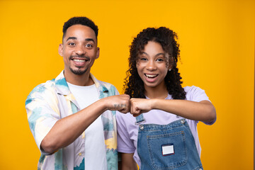 Obraz premium Two hipster friends smiling cheerfully while standing against a yellow background.