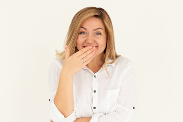 A pretty young woman covers her mouth with her hand while nervously laughing. Cute Caucasian girl giggles with her hand close to her lips. Concept of fun, pranks, joking around