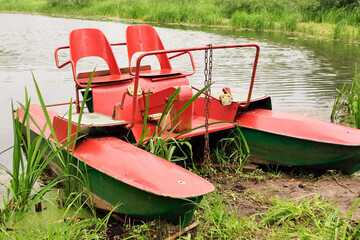 A red catamaran stands on the shore waiting