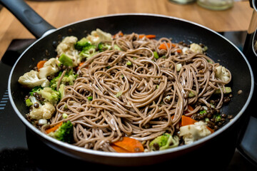 Chef at the kitchen preparing japanese buckwheat pasta with lentils