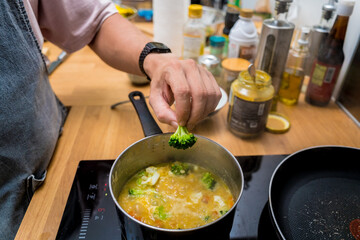 Chef at the kitchen preparing lentils soup with cauliflower and broccoli
