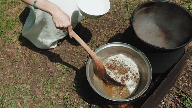 Woman with a spoon mixes empty shells from garden snails in a saucepan, which are cooked for cleaning in boiling water. The process of cooking a gourmet dish. French cuisine. Close-up. 
