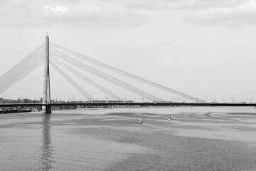 Fototapeta premium Black and white image of a bridge over a river in the morninging