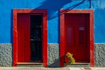 Obraz premium Buildings, street and parked bicycle on blue sky background. Colonial style of the city. Houses painted with various bright colors. Red barrels