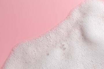 White fluffy foam on pink background, top view. Space for text
