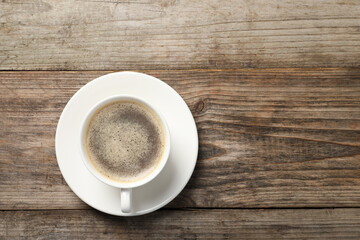 Tasty coffee in cup on wooden table, top view. Space for text