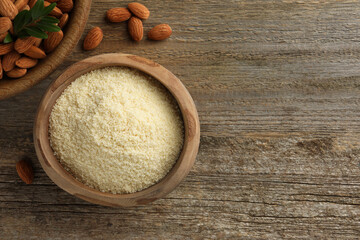 Fresh almond flour, branch and nuts on wooden table, flat lay. Space for text