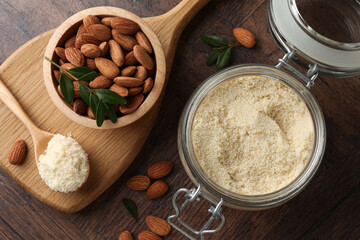 Fresh almond flour in jar, spoon and nuts on wooden table, flat lay