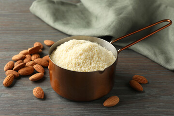 Fresh almond flour in scoop and nuts on wooden table, closeup