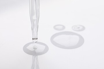 Glass pipette and transparent liquid on white background, closeup
