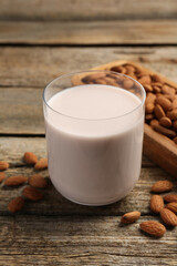 Glass of almond milk and almonds on wooden table