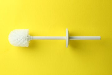 Toilet brush on yellow background, top view