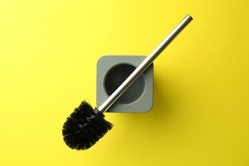 Toilet brush with holder on yellow background, top view