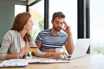 Fototapeta premium Couple, credit card and laptop at table for budget in morning with stress for online payment in house. People, banking and finance with bills, taxes and monthly payments for debt in apartment.
