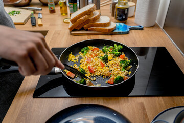 Chef at the kitchen preparing tofu scramble with vegetables