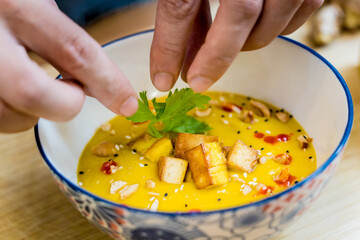 Chef at the kitchen preparing pumpkin porridge with tofu and vegetables