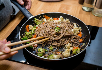 Chef at the kitchen preparing japanese buckwheat pasta with lentils