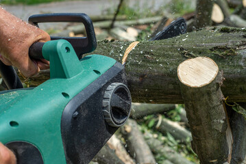 A male uses a chainsaw to cut up a log into firewood.