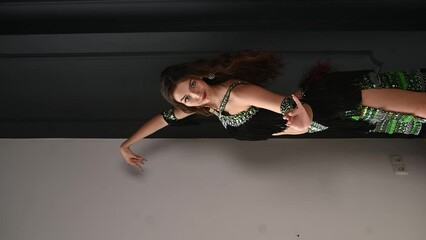 A girl in a black sparkly dress dances east Dance. 