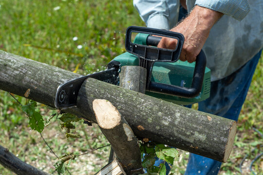 A male uses a chainsaw to cut up a log into firewood.