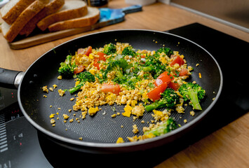 Chef at the kitchen preparing tofu scramble with vegetables