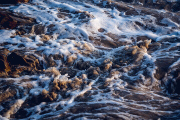 A large rocks surrounded by waves of the ocean