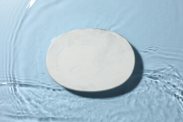 Presentation for product. White podium in water on light blue background, top view