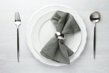 Stylish setting with cutlery, napkin and plates on light textured table, flat lay