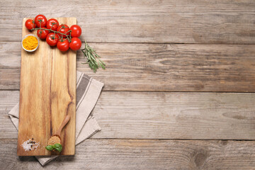 Cutting board, spices and tomatoes on wooden table, top view. Space for text