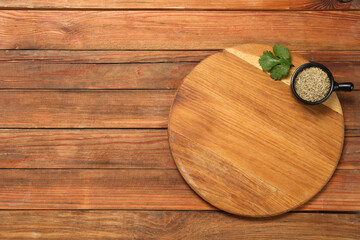 Cutting board, cumin and parsley on wooden table, top view. Space for text