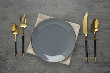 Elegant setting with golden cutlery on dark grey table, flat lay