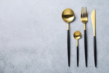 Stylish golden cutlery on grey table, flat lay. Space for text