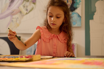 Fototapeta premium Young girl in art class painting and drawing with teacher guidance in an engaging workshop
