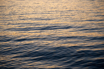 The wavy surface of the sea illuminated by the light of the sunset