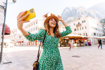 Pretty woman walks the streets and takes selfie using smartphone camera.  Travel, blogging,...