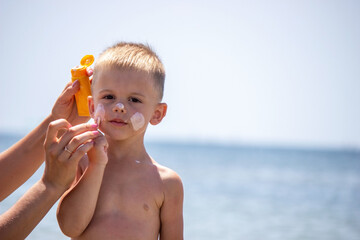 woman, mother applies sunscreen to the child. protection from the sun.