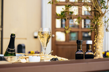 Elegant tall flute of chilled sparkling champagne with different snacks on an elegant formal dining table at outdoor cafe or restaurant in pedestrian street in Europe. Luxury served table at terrace.