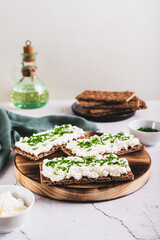 Homemade crispy rye toasts with ricotta and herbs on a board vertical view