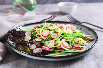 Fresh vitamin salad of cucumber and radish on a plate on the table